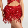 A woman wearing a red sequin hula dancer skirt with tassel belts.