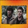 Two young men in leather jackets posing for a photo against a blurred outdoor background.