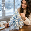 A woman is decorating a sparkling blue crystal bead Christmas tree kit with lights and ornaments.