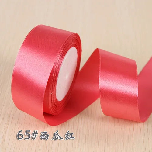 A roll of bright red silk satin ribbon used for gift wrapping and craft projects.
