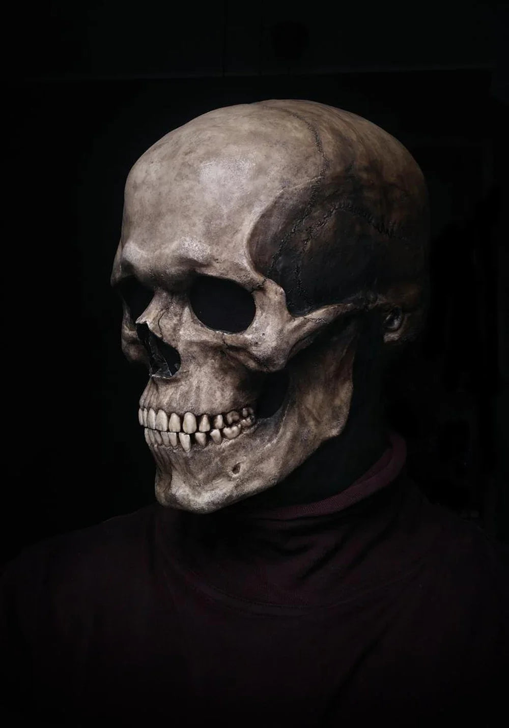 A realistic latex skull cosplay mask displayed on a dark background.