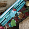 A blue advent calendar box with twelve compartments featuring book-themed ornaments and a festive plaid background.