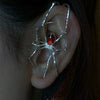 Silver spider ear cuff with a red gemstone detail worn on the ear.