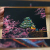 A DIY scratch painting art kit featuring a vibrant pink and green depiction of a traditional Japanese temple on a black backg
