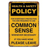 A vintage yellow metal sign with black text that reads Health & Safety Policy and Common Sense.