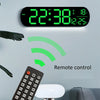 Reloj de pared digital LED RGB mostrando 22:38, temperatura y humedad, con control remoto cercano.