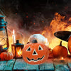 An orange carved pumpkin decoration with a spooky face sits on a rustic wooden surface surrounded by glowing candles and smok