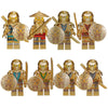 A set of five golden ninja building block figures with swords and circular emblems.