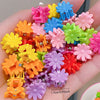 A collection of colorful flower and star hair claw clips for kids displayed on a hand.