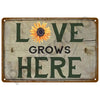 Vintage metal tin sign with the text LOVE GROWS HERE and a sunflower design.
