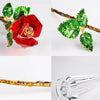 Handcrafted crystal glass rose vase with red rose and golden leaves on a branch.