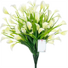 A bouquet of white artificial calla lilies with green stems and a small tag