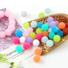 A collection of colorful textured resin beads in various shades of pink, blue, green, and orange are displayed on a wooden tr