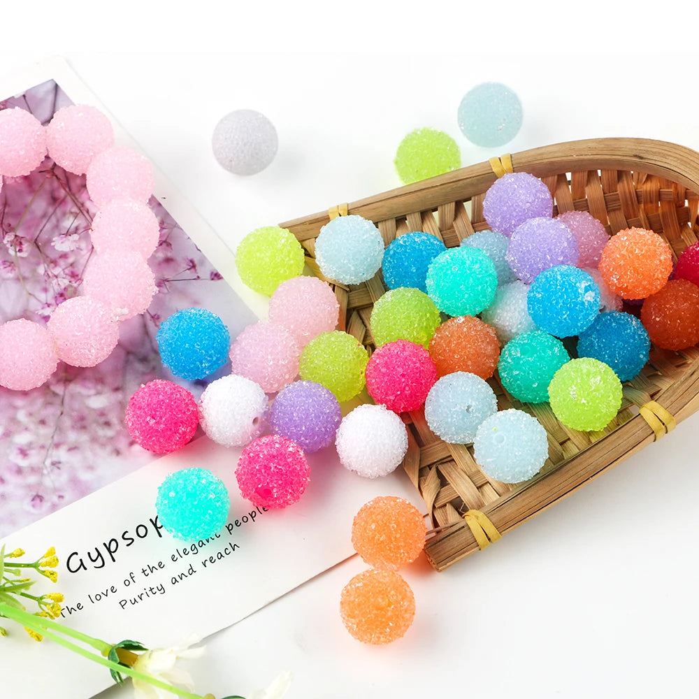 A collection of colorful textured resin beads in various shades of pink, blue, green, and orange are displayed on a wooden tr