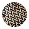 Round woven straw wall decor hanging with a black and natural beige chevron pattern