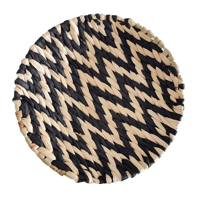 Round woven straw wall decor hanging with a black and natural beige chevron pattern