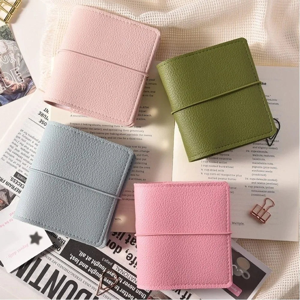 A stack of pink and green faux leather photo albums resting on a white fabric background.