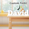 A wooden table with a personalized name ornament labeled David and decorative elements in the background.