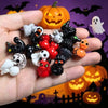 A hand holds a collection of quirky mini resin duck figurines with spooky designs in various colors like black, orange, and w
