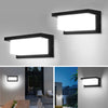A black rectangular wall sconce with a bright white light illuminates a white wall.