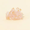 A cluster of pink quartz crystals with gold inclusions used as a Reiki amulet or decorative figurine.
