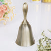 A polished brass hand call bell with a flared, conical shape resting on a white surface.