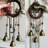 A pair of vintage wicker key bells with dark brown twine and brass accents hanging on a white door.