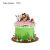 A green cake decorated with a bear and rabbit topper, surrounded by green grass and red mushrooms.
