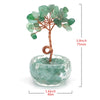 A crystal healing gemstone bonsai featuring green jade-like leaves growing from a wooden branch in a clear glass bowl.