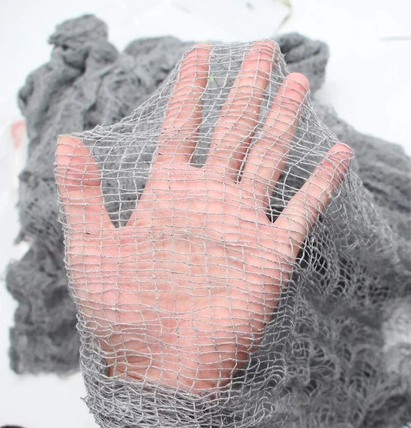 A hand is visible through a mesh of black creepy gauze cloth used for Halloween decor.
