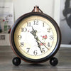A vintage metal battery alarm clock night light with a round face and dark wood casing sits on a surface.