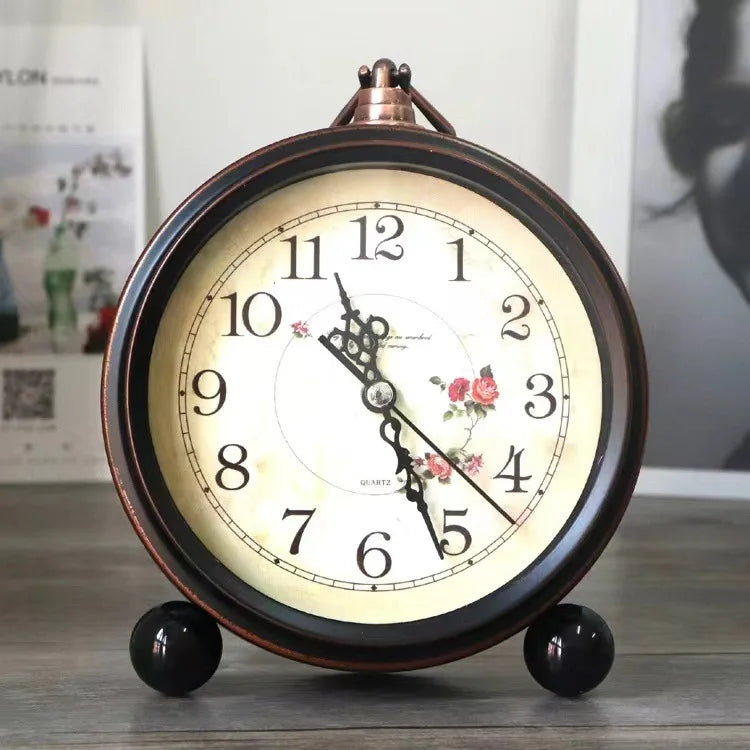 A vintage metal battery alarm clock night light with a round face and dark wood casing sits on a surface.