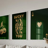 Three framed art prints featuring the text LUCKY YOU in gold lettering on a dark green background