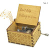 A vintage hand-cranked wooden music box with a lid engraved 'Can't Help Falling in Love' and a decorative wooden base.