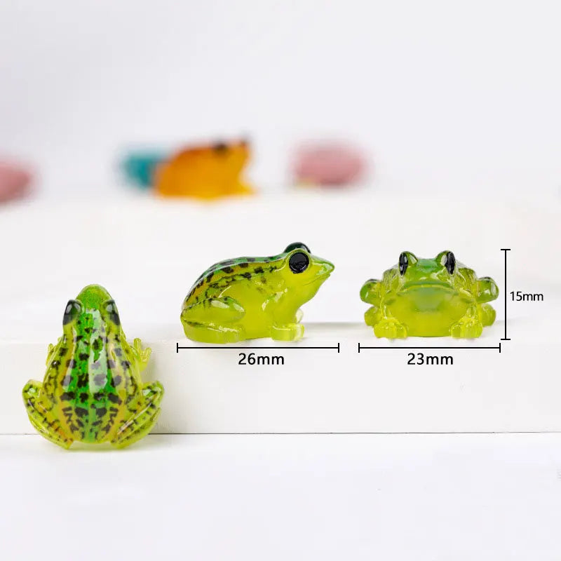 A set of glow-in-the-dark resin frog ornaments in various shades of green and yellow, showing their size.