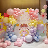 A display of pastel rainbow latex balloons in various shades of pink, yellow, and blue arranged in clusters.