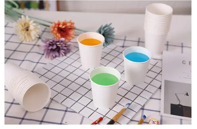 A collection of white disposable paper cups filled with various colored drinks, including orange, blue, and green.