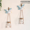 Two decorative glass terrariums featuring painted blue and white birds hanging on a wall
