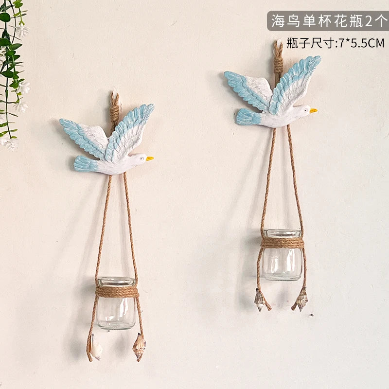 Two decorative glass terrariums featuring painted blue and white birds hanging on a wall