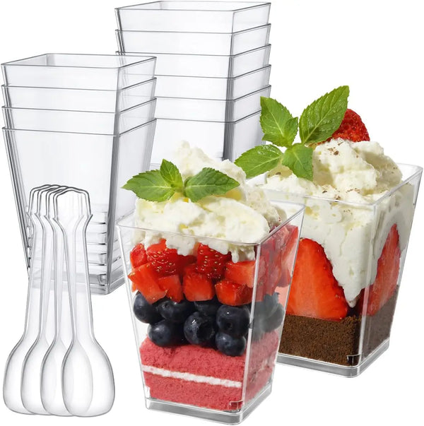A set of six clear glass mini dessert cups with spoons, some filled with fruit and cream.
