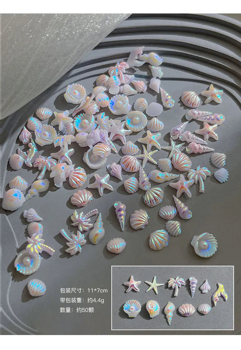 Colección de 50 mini charms de uñas de tortuga coloridas en tonos iridiscentes y pastel sobre una superficie gris.