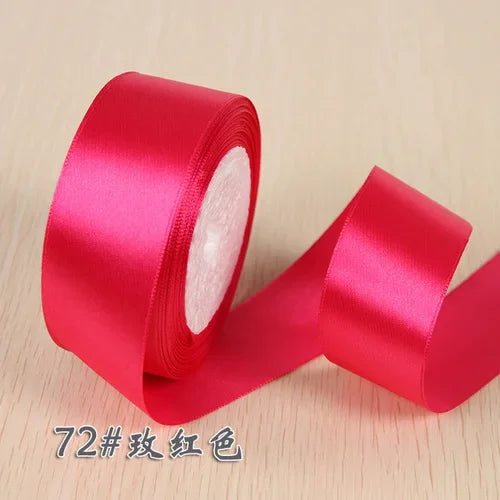 A roll of bright pink silk satin ribbon used for gift wrapping and craft projects.