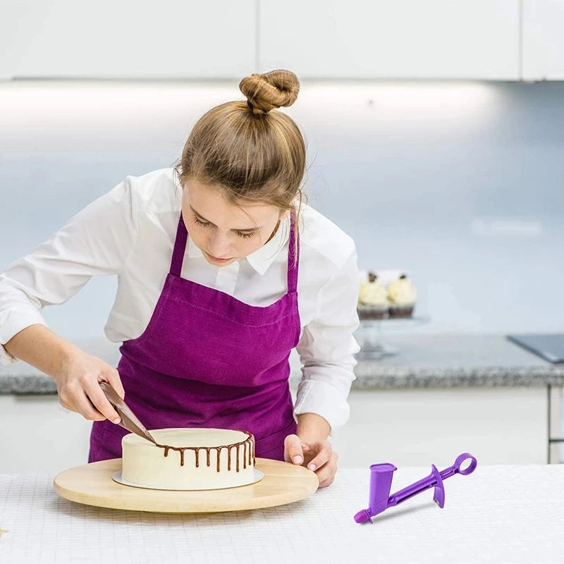A young woman applies a pearl ball using a purple applicator tool on a cake decorated with fondant.