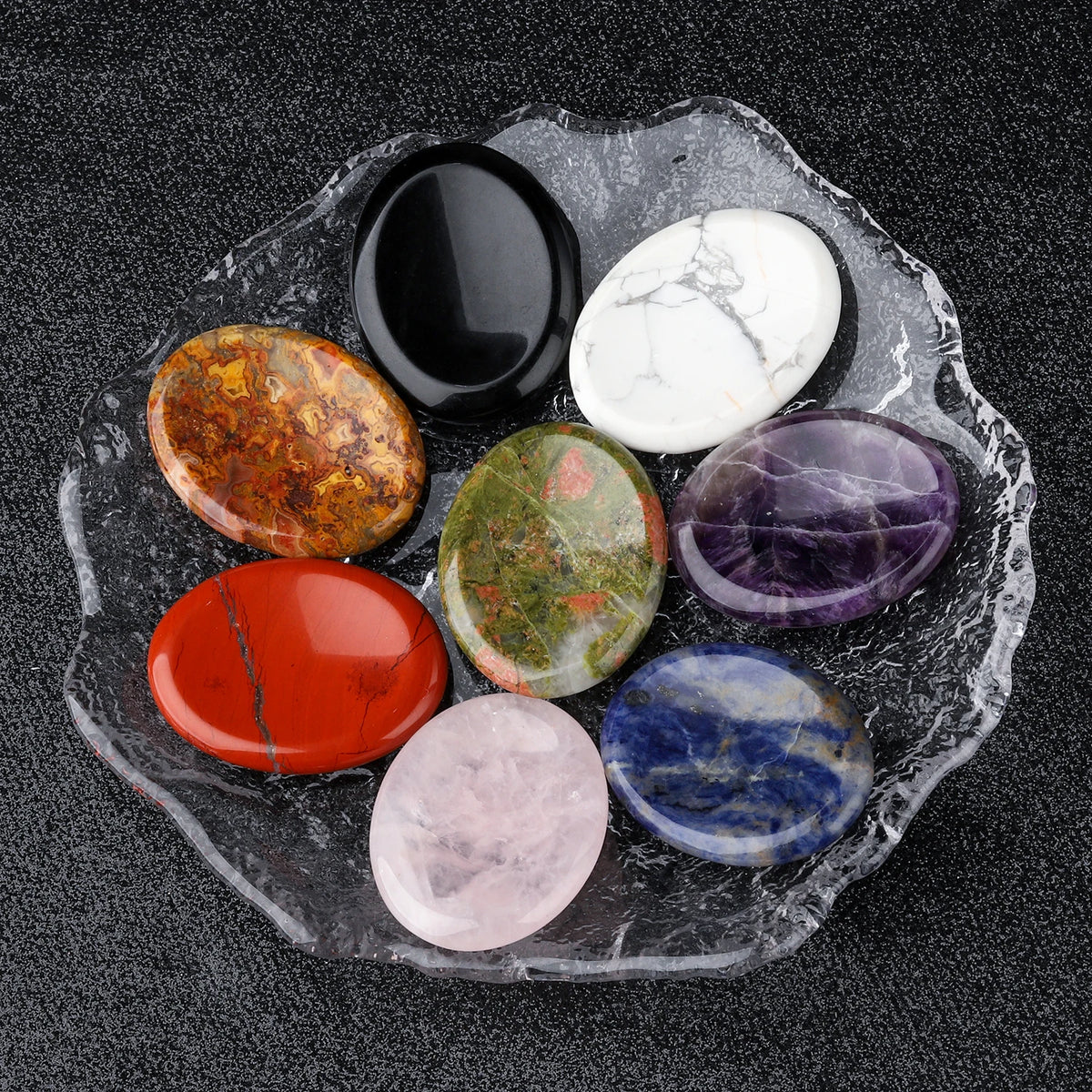 A collection of polished natural stone oval beads in various colors including black, white, purple, green, orange, and blue, 