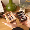 A hand holds a small wooden photo frame displaying a polaroid picture.