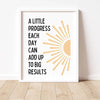 A framed print with the quote A little progress each day can add up to big results featuring a sunburst design.