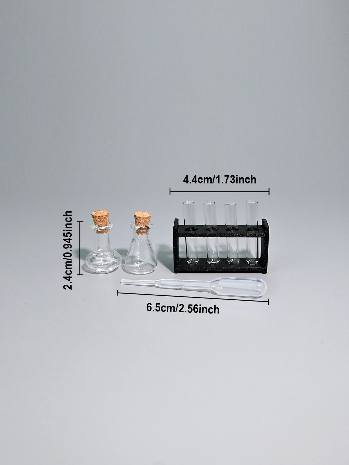 A miniature laboratory set featuring glass vials, a pipette, and various sized tubes for dollhouse or photography.