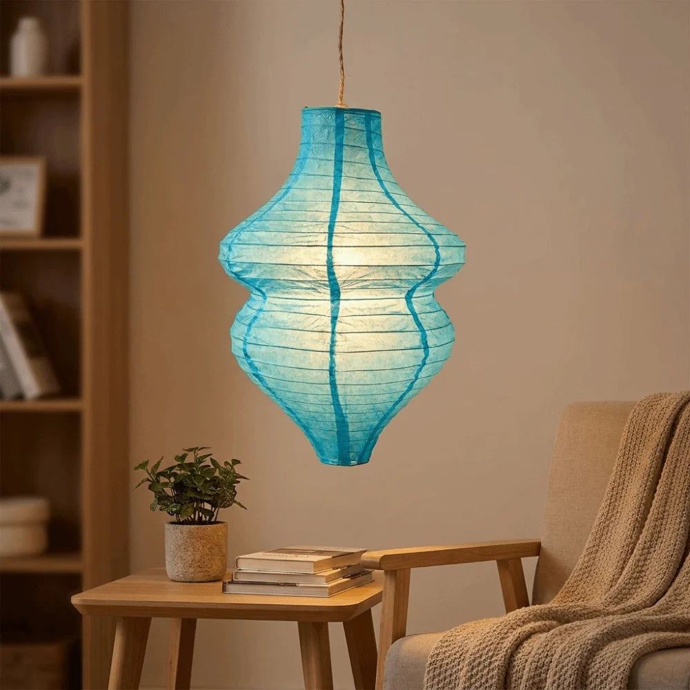 Linterna de vidrio turquesa en forma de flor, colgando contra una pared clara.