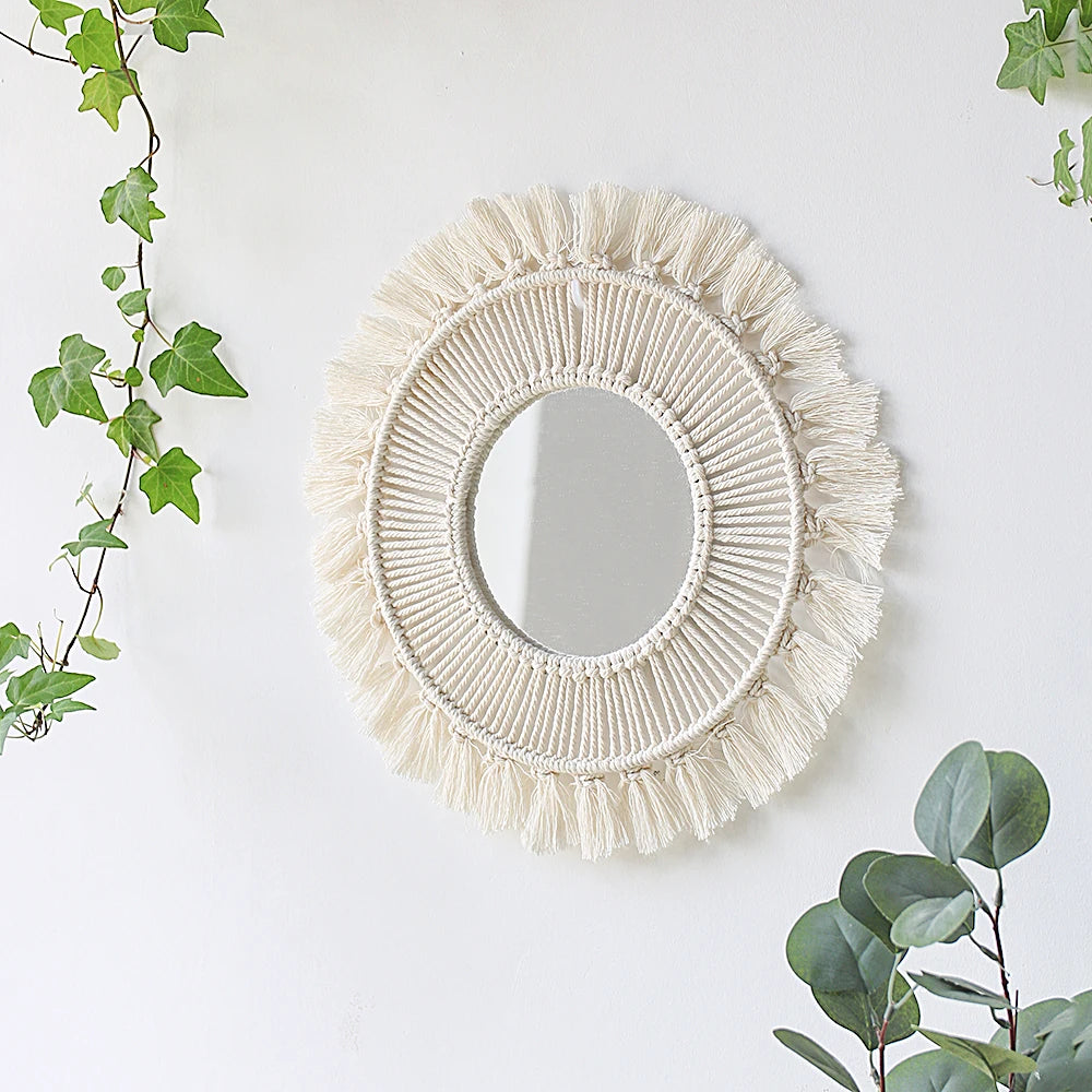 Miroir mural en macramé rond avec une bordure frangée de couleur crème, fixé sur un mur blanc.