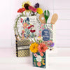 A ceramic book-shaped vase filled with colorful flowers and featuring a vintage gold pattern.